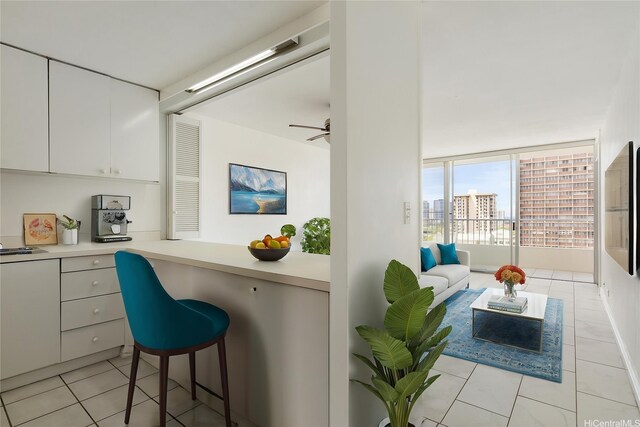 1515 Ward Ave Unit 304, Honolulu, HI 96822 - kitchen with light tile patterned floors, light countertops, white cabinets, a breakfast bar area, and ceiling fan