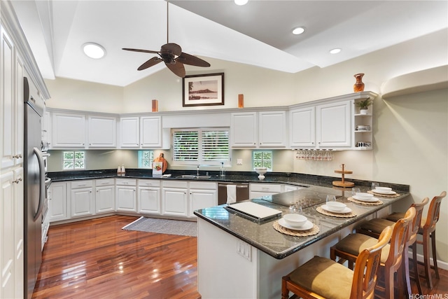 kitchen featuring dishwasher, a peninsula, a ceiling fan, white cabinets, and lofted ceiling