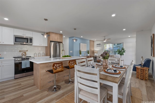 92-370 Malahuna Pl, Kapolei, HI 96707 - kitchen featuring stainless steel appliances, light wood-style floors, light countertops, a kitchen island with sink, and decorative backsplash