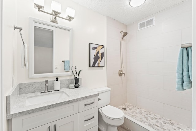 1556 Piikoi St Unit 1802, Honolulu, HI 96822 - bathroom featuring toilet, a tile shower, a textured ceiling, and vanity