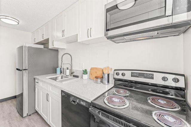 1556 Piikoi St Unit 1802, Honolulu, HI 96822 - kitchen featuring stainless steel appliances, a sink, white cabinets, light wood finished floors, and a textured ceiling