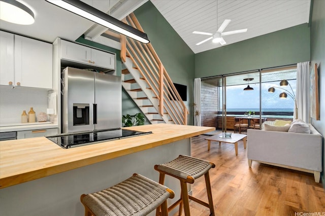 51-636 Kamehameha Hwy Unit 323, Kaaawa, HI 96730 - kitchen with stainless steel fridge, wood counters, black electric cooktop, light wood-style floors, and a breakfast bar area