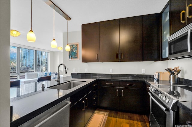 1189 Waimanu St Unit 1606, Honolulu, HI 96814 - kitchen with appliances with stainless steel finishes, dark wood finished floors, hanging light fixtures, dark brown cabinetry, and dark stone countertops