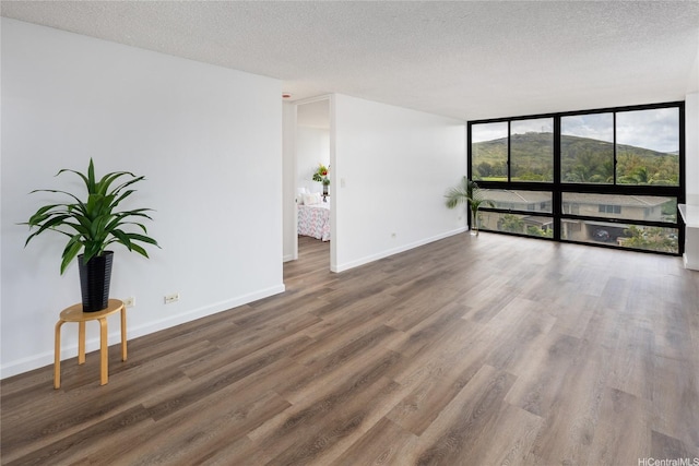 3070 Ala Ilima St Unit 306, Honolulu, HI 96818 - unfurnished room featuring a wall of windows, wood finished floors, a textured ceiling, and baseboards