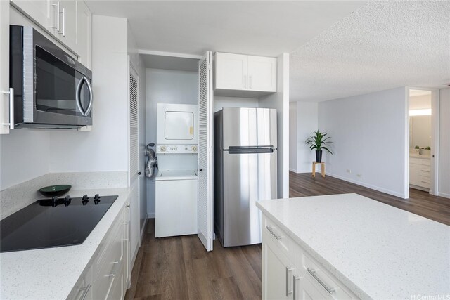 3070 Ala Ilima St Unit 306, Honolulu, HI 96818 - kitchen featuring appliances with stainless steel finishes, stacked washer / drying machine, dark wood-style floors, light stone countertops, and a textured ceiling