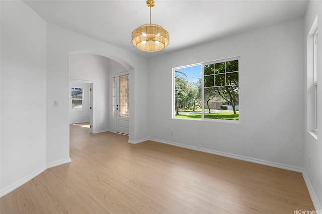 91-1023 Kaikoele St, Ewa Beach, HI 96706 - empty room with arched walkways, light wood-style flooring, a chandelier, and baseboards