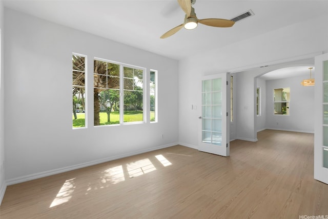 91-1023 Kaikoele St, Ewa Beach, HI 96706 - empty room featuring arched walkways, light wood-type flooring, baseboards, ceiling fan, and french doors