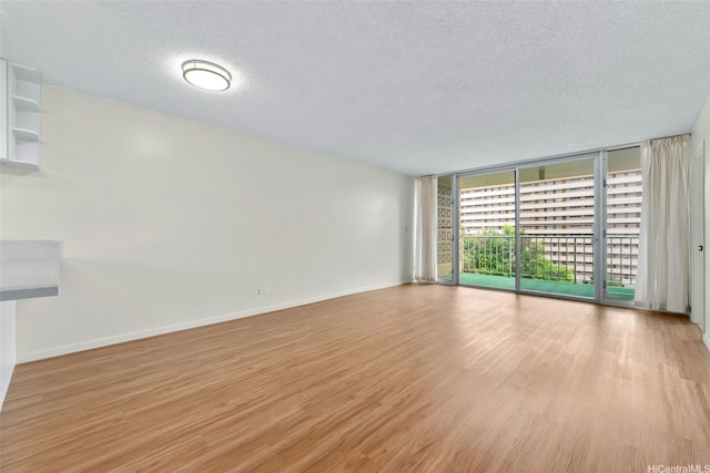 3020 Ala Napuaa Pl Unit 103, Honolulu, HI 96818 - unfurnished room with floor to ceiling windows, a textured ceiling, light wood-type flooring, and baseboards