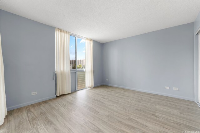 3020 Ala Napuaa Pl Unit 103, Honolulu, HI 96818 - empty room featuring light wood-style floors, a textured ceiling, and baseboards