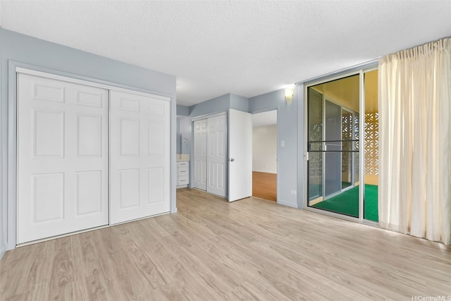 3020 Ala Napuaa Pl Unit 103, Honolulu, HI 96818 - unfurnished bedroom with wood finished floors, access to outside, a textured ceiling, baseboards, and floor to ceiling windows