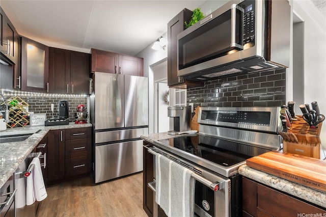 430 Keoniana St Unit 202, Honolulu, HI 96815 - kitchen with stainless steel appliances, backsplash, light stone counters, dark brown cabinetry, and light wood finished floors