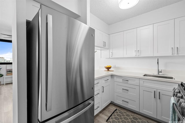1571 Piikoi St Unit 503, Honolulu, HI 96822 - kitchen featuring appliances with stainless steel finishes, a sink, a textured ceiling, light countertops, and light wood-style flooring