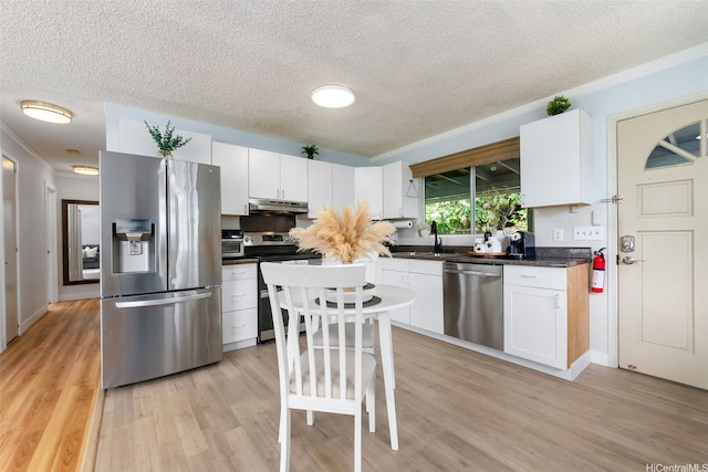 1681 Mahani Loop, Honolulu, HI 96819 - kitchen featuring appliances with stainless steel finishes, a textured ceiling, under cabinet range hood, white cabinets, and dark countertops
