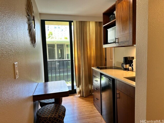2425 Kuhio Ave Unit 410, Honolulu, HI 96815 - kitchen with light wood-style flooring, a textured wall, light countertops, black electric stovetop, and open shelves