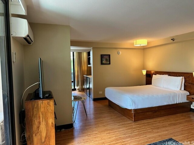 2425 Kuhio Ave Unit 410, Honolulu, HI 96815 - bedroom featuring light wood-style flooring, a wall mounted air conditioner, and baseboards
