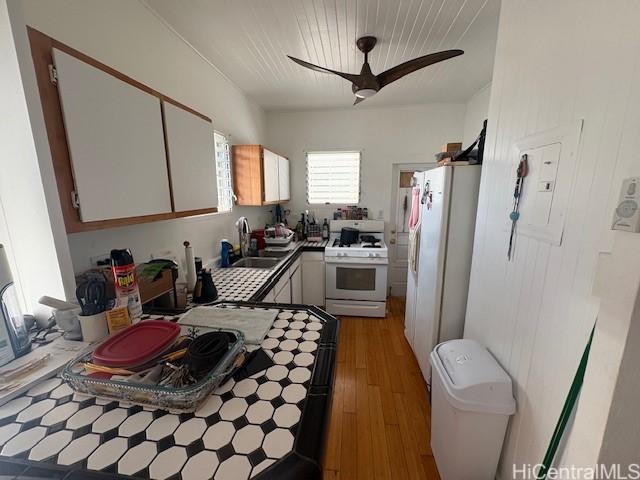 1704 Kamamalu Ave, Honolulu, HI 96813 - kitchen with white appliances, wood finished floors, electric panel, ceiling fan, and white cabinetry