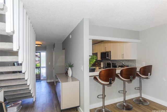 444 Lunalilo Home Rd Unit 226, Honolulu, HI 96825 - kitchen with stainless steel microwave, dark wood finished floors, tasteful backsplash, a textured ceiling, and baseboards