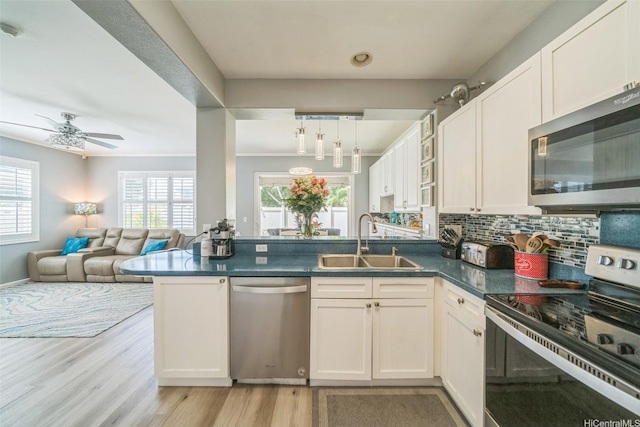 91-2222 Kanela St Unit T88, Ewa Beach, HI 96706 - kitchen featuring appliances with stainless steel finishes, a sink, a peninsula, dark countertops, and light wood-style flooring