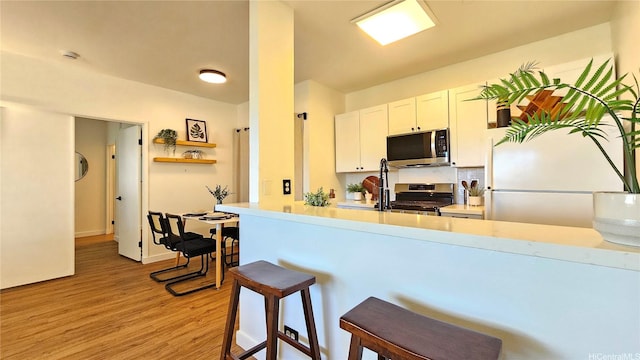 91-540 Puamaeole St Unit 49D, Ewa Beach, HI 96706 - kitchen featuring stainless steel appliances, light wood finished floors, a kitchen breakfast bar, light countertops, and white cabinets