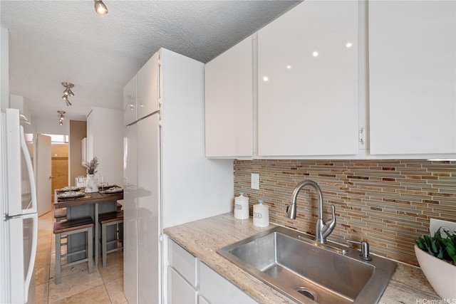 1670 Kalakaua Ave Unit 205, Honolulu, HI 96826 - kitchen with freestanding refrigerator, white cabinetry, tasteful backsplash, light stone counters, and light tile patterned floors