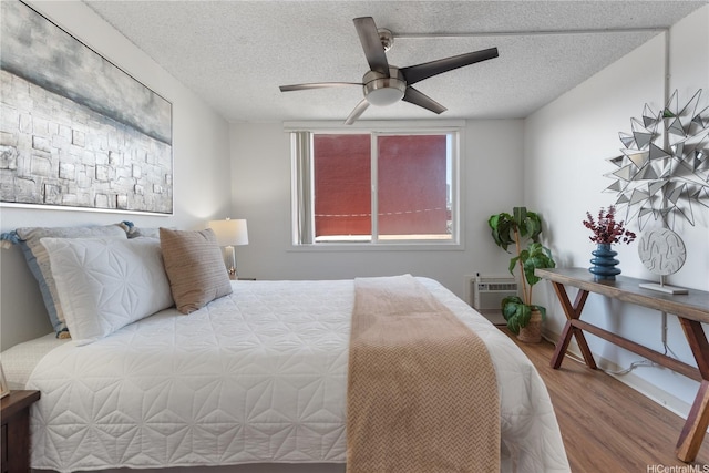 1670 Kalakaua Ave Unit 205, Honolulu, HI 96826 - bedroom featuring wood finished floors, a wall unit AC, a textured ceiling, and ceiling fan