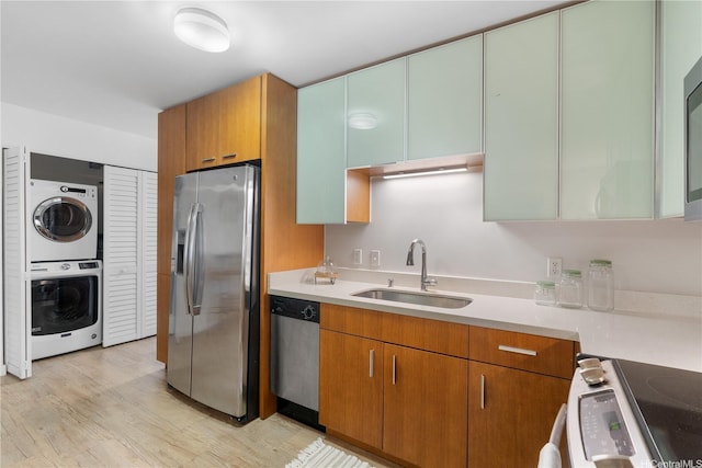 1310 Pensacola St Unit 106, Honolulu, HI 96814 - kitchen with appliances with stainless steel finishes, a sink, estacked washer and dryer, light countertops, and light wood finished floors
