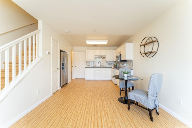 91-1031 Kaimalie St Unit 4P4, Ewa Beach, HI 96706 - kitchen featuring appliances with stainless steel finishes, light wood-type flooring, decorative backsplash, and baseboards