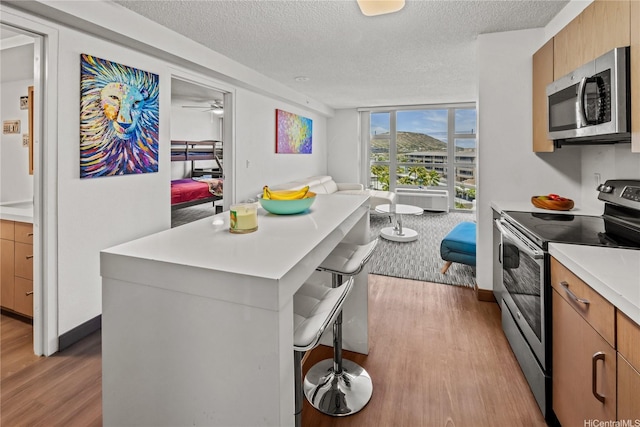 7000 Hawaii Kai Dr Unit 2702, Honolulu, HI 96825 - kitchen featuring stainless steel appliances, wood finished floors, a textured ceiling, light countertops, and open floor plan