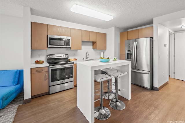 7000 Hawaii Kai Dr Unit 2702, Honolulu, HI 96825 - kitchen featuring stainless steel appliances, light wood-style floors, a kitchen breakfast bar, light countertops, and a textured ceiling