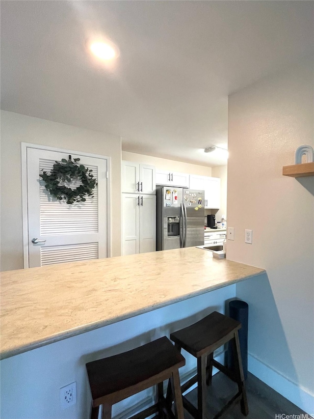 91-1227 Kamaaha Ave Unit 302, Kapolei, HI 96707 - kitchen with stainless steel fridge, a breakfast bar area, white cabinets, and light countertops