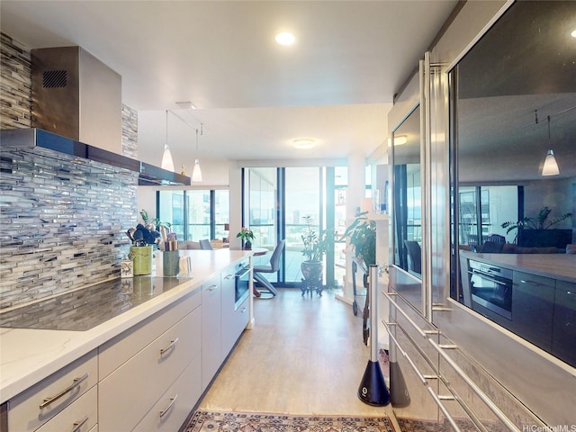 1015 Wilder Ave Unit 1003, Honolulu, HI 96822 - kitchen featuring light wood-style flooring, wall chimney exhaust hood, white cabinets, decorative backsplash, and decorative light fixtures