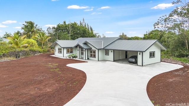 ranch-style home with concrete driveway, metal roof, and a carport
