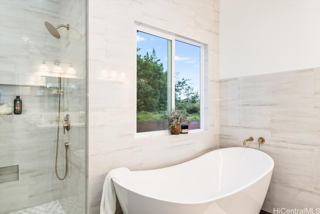 bathroom with tile walls, a shower stall, and a freestanding tub