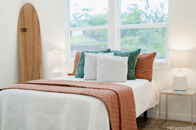 bedroom with multiple windows and wood finished floors