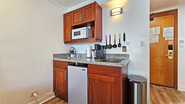 2425 Kuhio Ave Unit 603, Honolulu, HI 96815 - kitchen featuring white microwave, wood finished floors, crown molding, freestanding refrigerator, and light stone counters