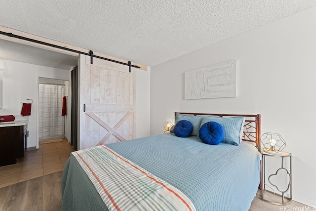 2452 Tusitala St Unit 1101, Honolulu, HI 96815 - bedroom with a barn door, a textured ceiling, wood finished floors, and ensuite bathroom