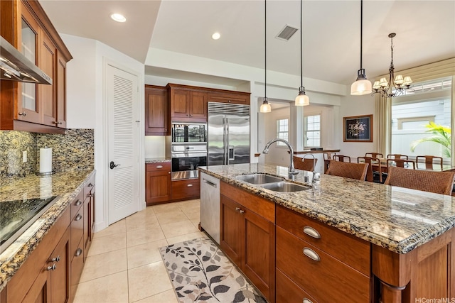 91-1338 Kaiokia St, Ewa Beach, HI 96706 - kitchen featuring built in appliances, wall chimney range hood, a center island with sink, hanging light fixtures, and light tile patterned floors