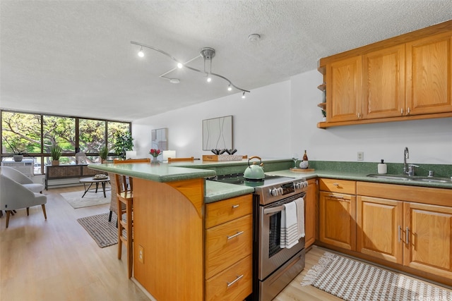 3138 Waialae Ave Unit 521, Honolulu, HI 96816 - kitchen with stainless steel electric stove, a sink, a peninsula, light wood-style floors, and brown cabinetry