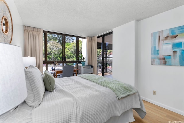 3138 Waialae Ave Unit 521, Honolulu, HI 96816 - bedroom featuring a wall of windows, wood finished floors, a textured ceiling, baseboards, and cooling unit