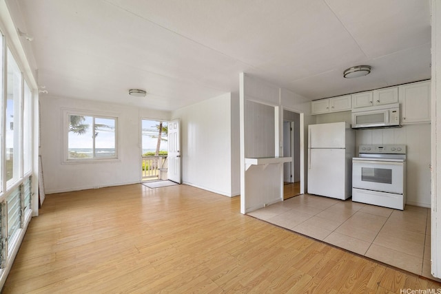 54-011 Waikulama St, Hauula, HI 96717 - kitchen with white appliances, white cabinetry, light wood finished floors, and open floor plan