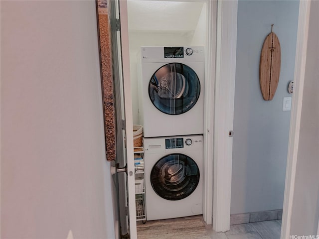 laundry room featuring stacked washer and clothes dryer and baseboards