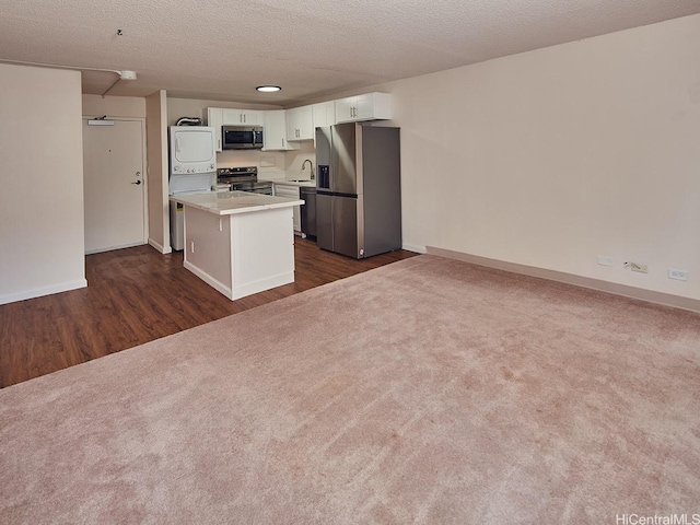 1333 Heulu St Unit 408, Honolulu, HI 96822 - kitchen with appliances with stainless steel finishes, stacked washing machine and dryer, a sink, dark wood-style flooring, and white cabinetry