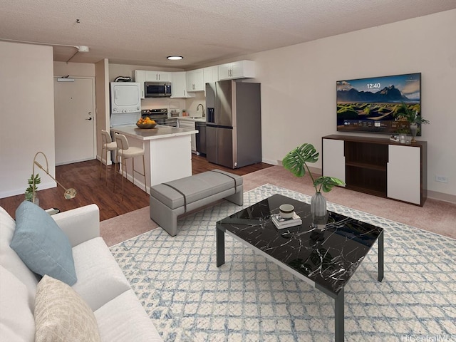 1333 Heulu St Unit 408, Honolulu, HI 96822 - living room featuring stacked washer / drying machine, baseboards, a textured ceiling, and dark wood-style flooring