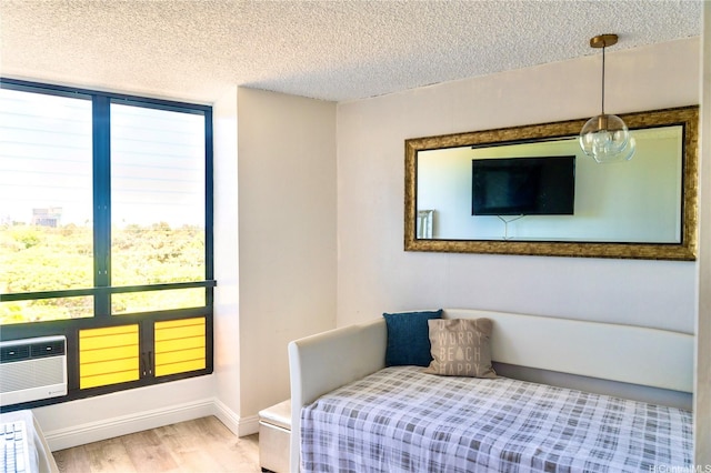 134 Kapahulu Ave Unit 707, Honolulu, HI 96815 - bedroom with a textured ceiling, light wood-type flooring, baseboards, and a wall unit AC