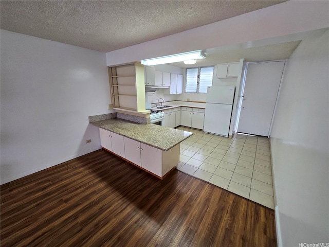 910 Kapahulu Ave Unit 303, Honolulu, HI 96816 - kitchen with white appliances, a peninsula, a sink, light wood-style floors, and white cabinets