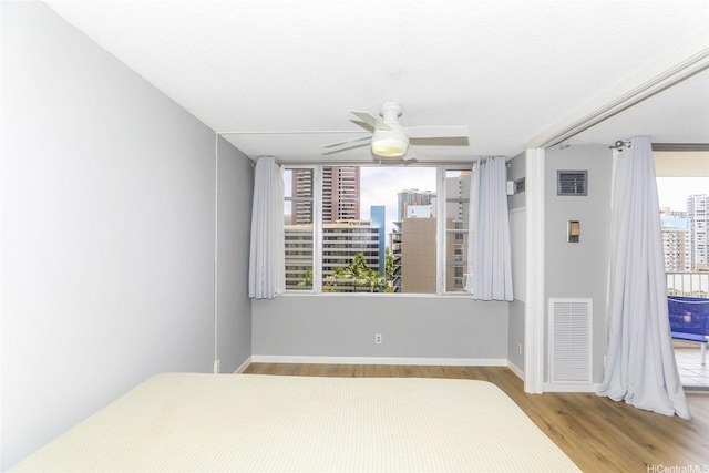 400 Hobron Ln Unit 1109, Honolulu, HI 96815 - unfurnished bedroom with wood finished floors, a city view, baseboards, and ceiling fan