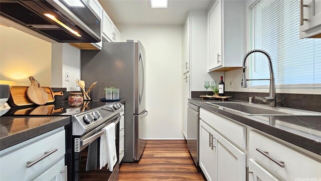 95-786 Wikao St Unit M103, Mililani, HI 96789 - kitchen featuring appliances with stainless steel finishes, wall chimney range hood, dark countertops, and white cabinets