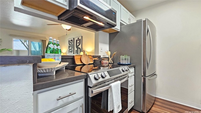 95-786 Wikao St Unit M103, Mililani, HI 96789 - kitchen with stainless steel electric stove, extractor fan, dark countertops, dark wood finished floors, and white cabinetry