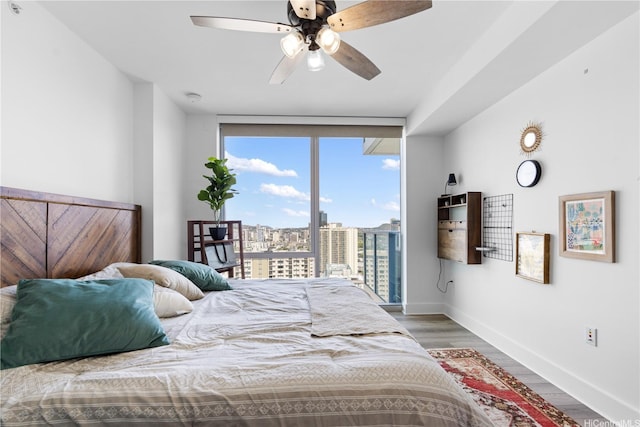 629 Keeaumoku St Unit 2505, Honolulu, HI 96814 - bedroom with baseboards, wood finished floors, expansive windows, access to exterior, and ceiling fan