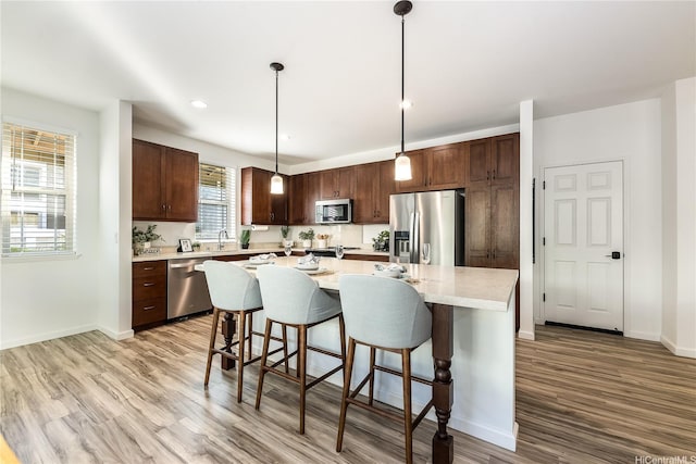 84-814 Maiola St Unit 39, Waianae, HI 96792 - kitchen featuring appliances with stainless steel finishes, light wood-style flooring, light countertops, a breakfast bar area, and recessed lighting